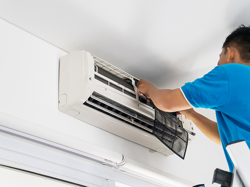 man repairing ac on wall kentwood mi